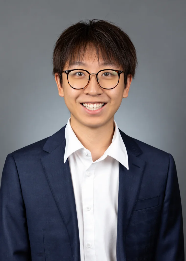 Yitong “Toby” Zheng smiling in a navy suit and glasses